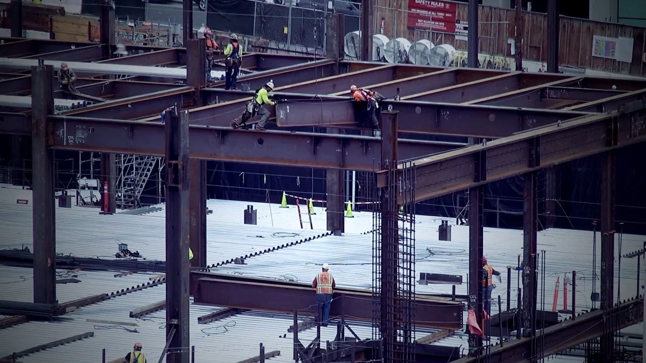 Ironworkers walking steel beams on a high structure