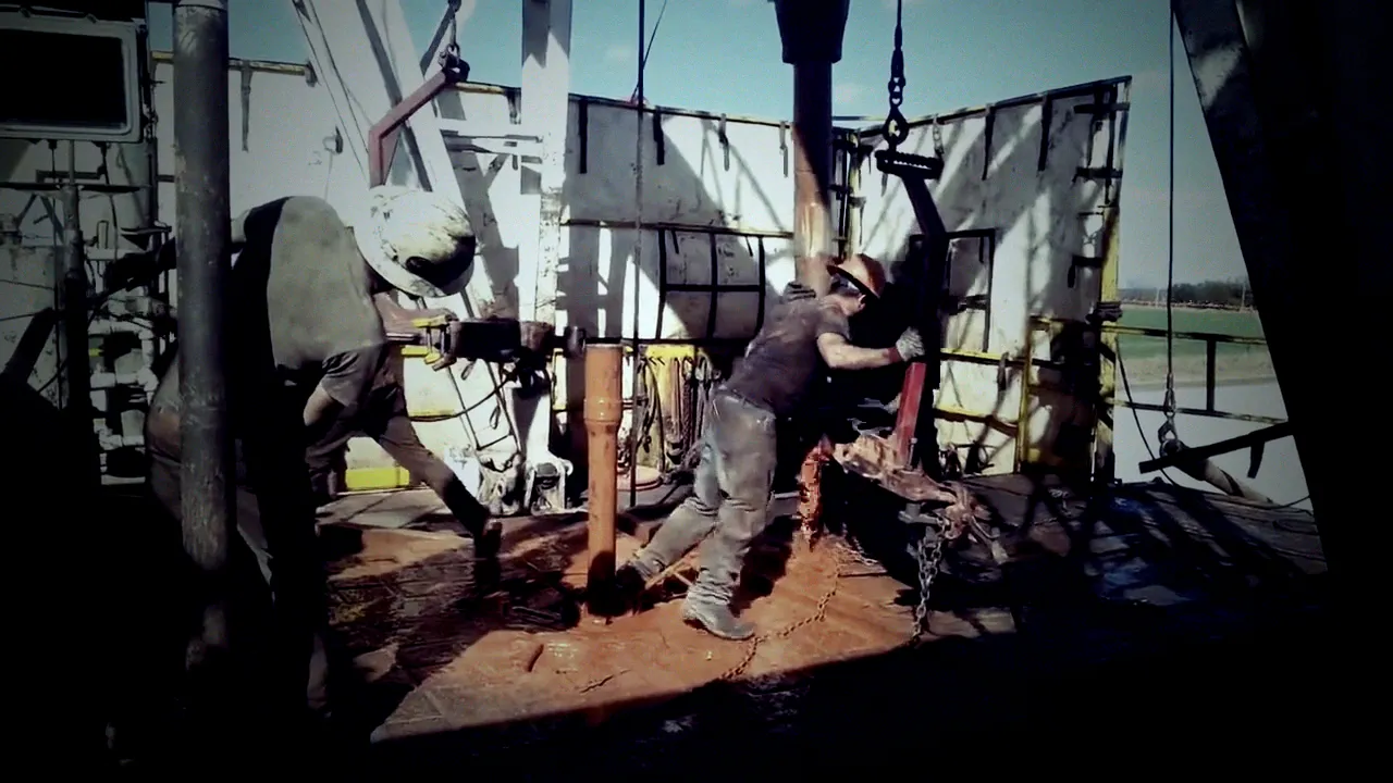 Roughnecks wrestling pipe on a drilling rig floor
